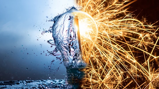 Image of a light bulb in the center of water on the left and sparks on the right