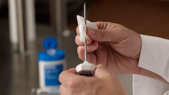 Hands cleaning and sanitizing a digital probe thermometer with cleaning wipes