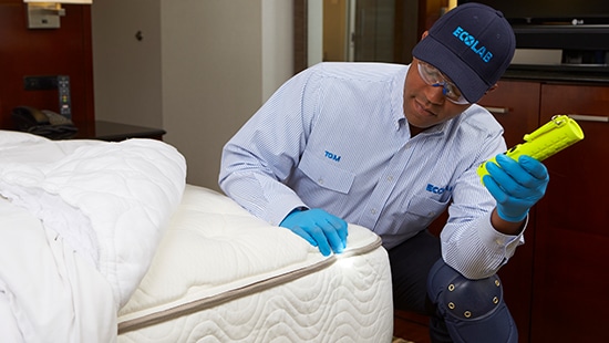 An Ecolab employee  treating a hotel  mattress for pests.