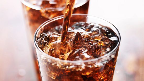 cola beverage poured into glass with ice
