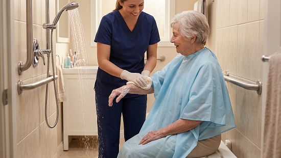 Caregiver showers patient in hospital in wheel chair