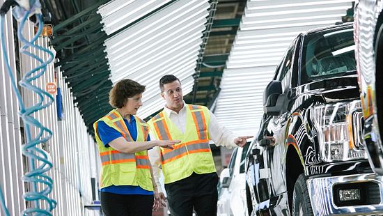 two team members inspecting production line of vehicles