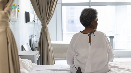 Older patient sitting on a hospital bed in a gown